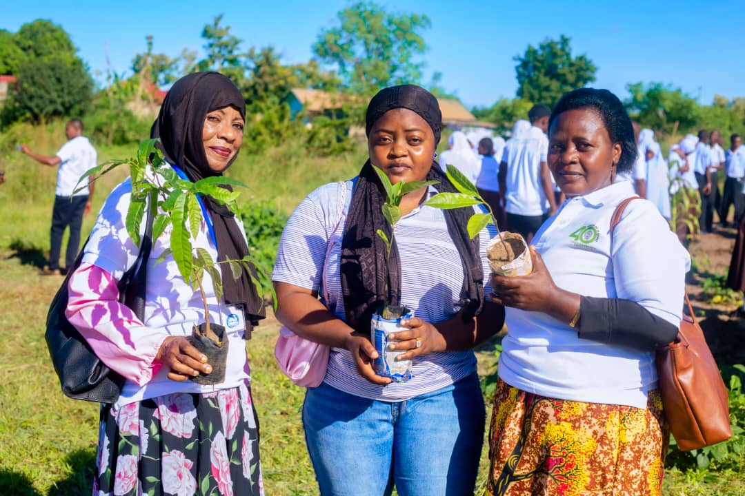 Community members holding potted seedlings at a tree planting drive