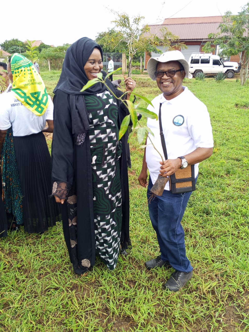 TAGET representative handing a tree seedling to a community leader